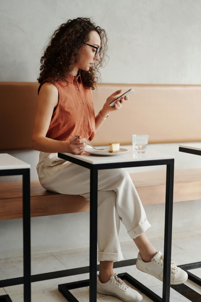 Woman looking at her phone while eating self-growth journey